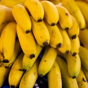 Cluster of bright yellow bananas stacked in a market, showcasing freshness and ripeness.